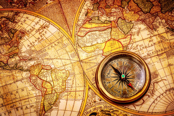 vintage compass lies on an ancient world map.