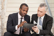 © BlueSkyImages - Two businesspeople sitting on stairs and looking at papers.