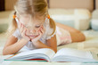 © altanaka - little girl lying on the bed and reading a book