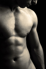 Man with naked muscled torso against black background