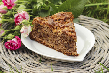 Piece of chocolate cake at garden party. Beautiful lush pink ros