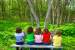 Children girls sitting on park bench looking at forest