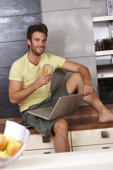 Wall Mural - Happy man browsing internet in kitchen