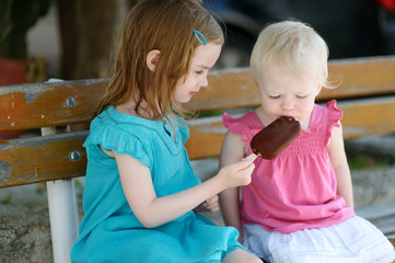 Wall Mural - Two little sisters eating ice cream