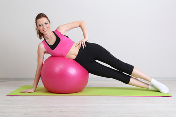 Portrait of beautiful young woman exercises with gym ball