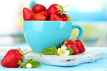 Wall Mural - Ripe sweet strawberries in cup on blue wooden table