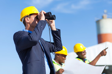 Wall Mural - architect using binoculars looking at construction site