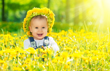 happy baby girl in a wreath on  meadow with yellow flowers  on t