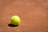 Fototapeta  - yellow tennis ball on orange sand