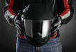 Motorcyclist with helmet in his hands. Dark background