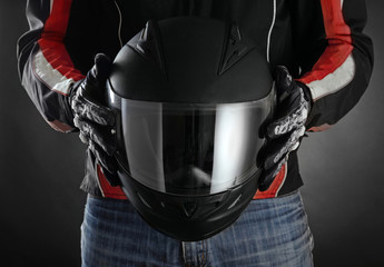 Fototapete - Motorcyclist with helmet in his hands. Dark background
