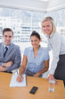 © WavebreakmediaMicro - Business people at desk with notepad smiling at camera