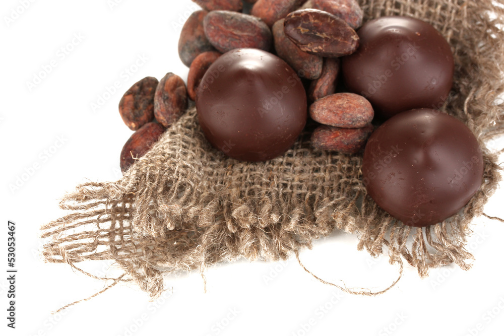 Chocolate candies and cocoa beans isolated on white