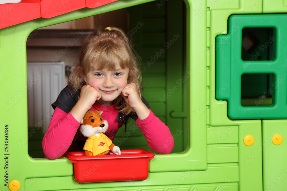 Dziewczynka w przedszkolu w oknie małego domku. - obrazy, fototapety, plakaty 