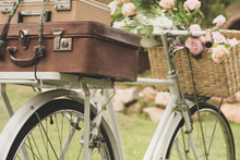 Vintage Bicycle On The Field With A Basket Of Flowers And Bag