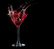 red cocktail splashing into glass on black