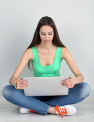 Wall Mural - Beautiful young woman sitting with laptop in room