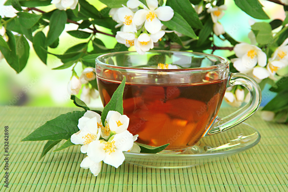 Cup of tea with jasmine, on bamboo mat, on bright background
