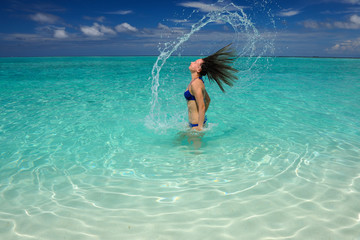 Woman splashing water with hair in the ocean