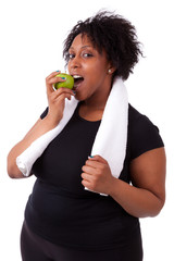 Wall Mural - Overweight young black woman eating an apple - African people