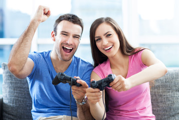 Wall Mural - Excited couple playing video games on the sofa