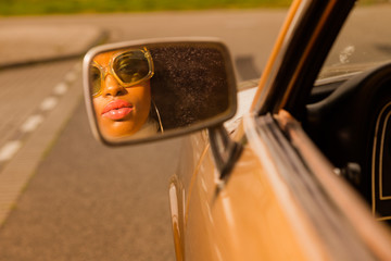 Retro 70s afro fashion woman with sunglasses looking in mirror o