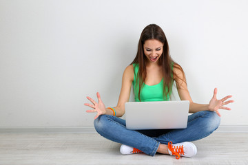 Canvas Print - Beautiful young woman sitting with laptop in room