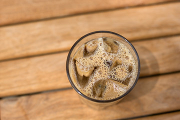 Cold ice coffee with cubes on wooden table