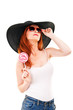 Girl with black hat holds lollipop.