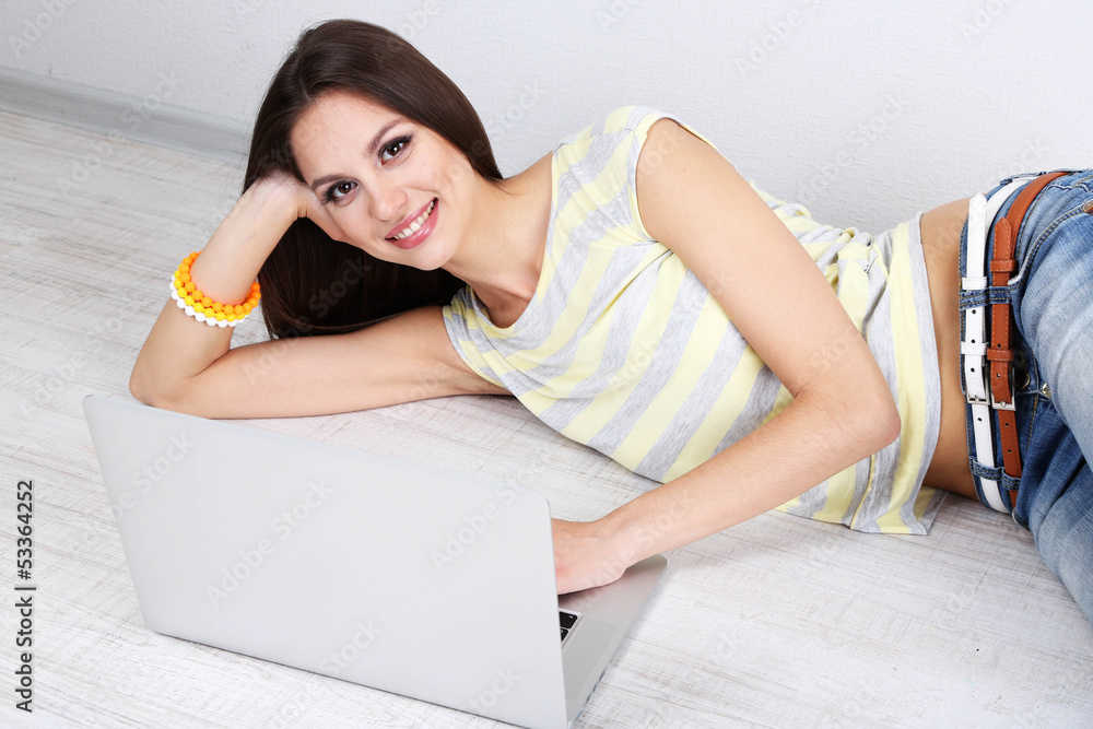 Beautiful young woman lying with laptop in room