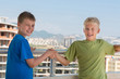 © Pavel Losevsky - Two smiling boys are shake hands on background of building