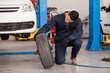 © AntonioDiaz - Male mechanic inspecting a car tire at an auto shop