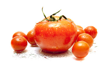 big red tomato among small tomatoes on white background