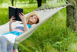 © stormy - Happy young woman reading in hammock in green park outdoors