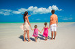 © travnikovstudio - Back view family of four on caribbean beach vacation