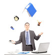 Young businessman in a suit juggling with office supplies in his