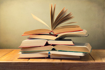 Wall Mural - Open old books on wooden table over grunge background