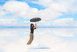 Young woman flying with umbrella on lake Salar de Uyuni