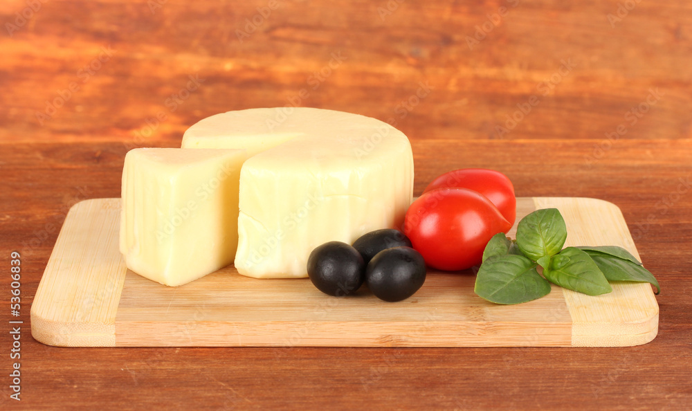 Cheese mozzarella,basil and vegetables on wooden background