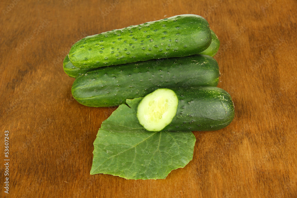 Tasty green cucumbers on wooden background
