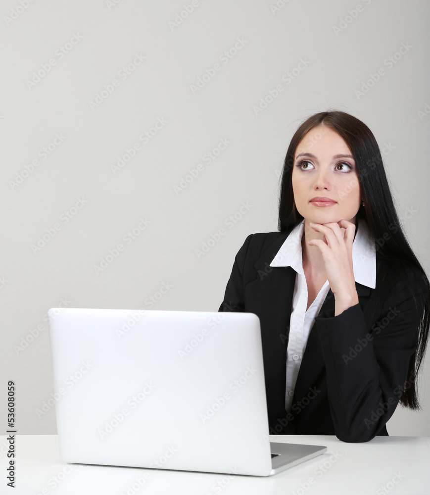Young business woman working with computer, on gray background