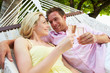 © Monkey Business - Couple Relaxing In Beach Hammock Drinking Champagne