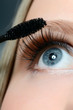 Woman applying mascara on her eyelashes - macro shot