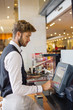 © onoky - Waiter using a computer at checkout counter in a restaurant