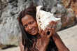 Young woman holding a conch shell to her ears