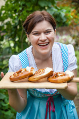 Wall Mural - Happy beautiful woman in dirndl dress holding pretzel