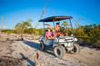© travnikovstudio - Dad and his two daughters driving golf cart at tropical beach