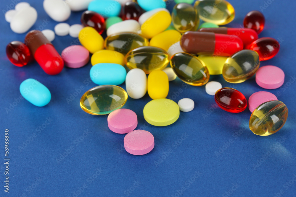Assortment of pills, tablets and capsules on blue background
