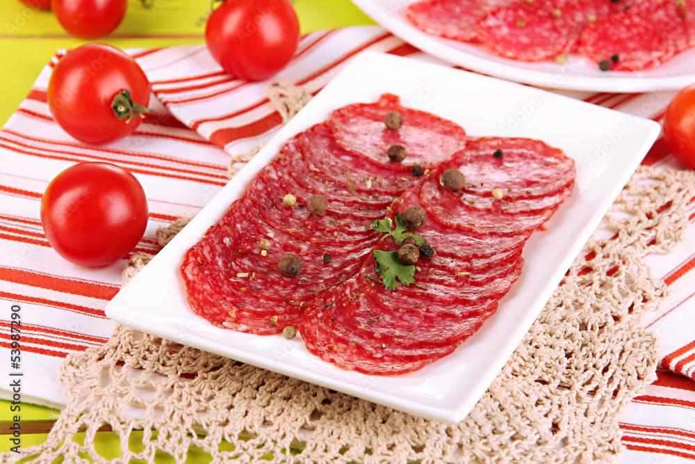 Tasty salami on plates on wooden table close-up