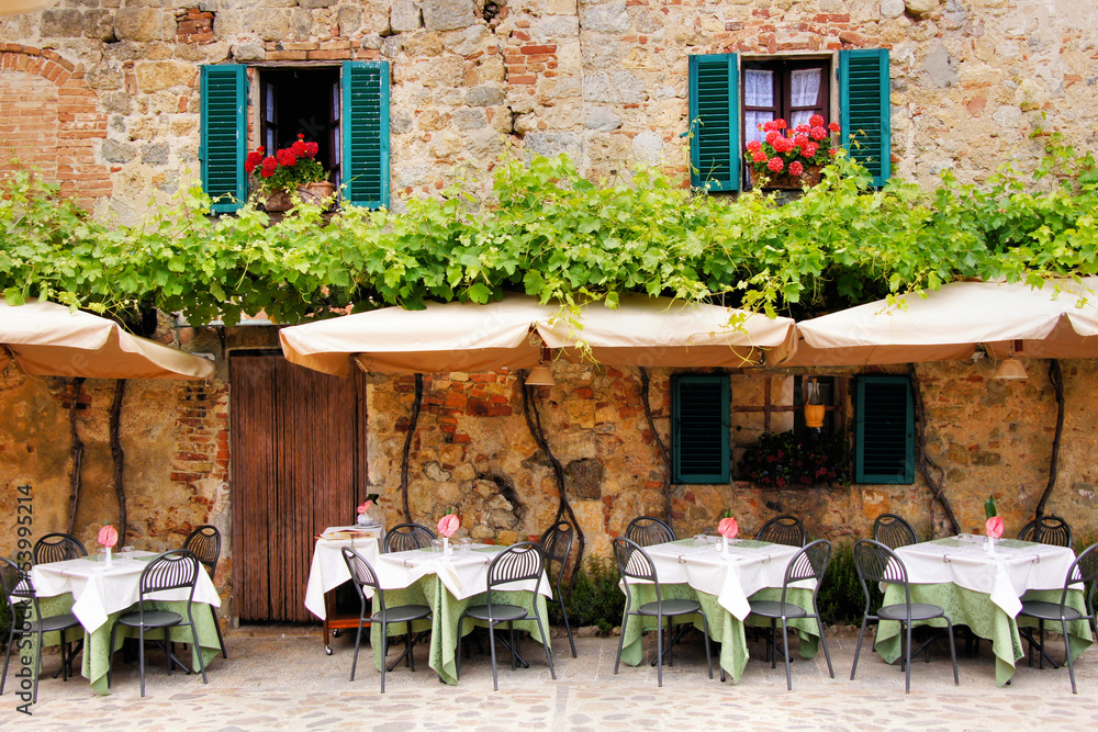 Cafe tables and chairs outside a stone building in Tuscany - obrazy, fototapety, plakaty 